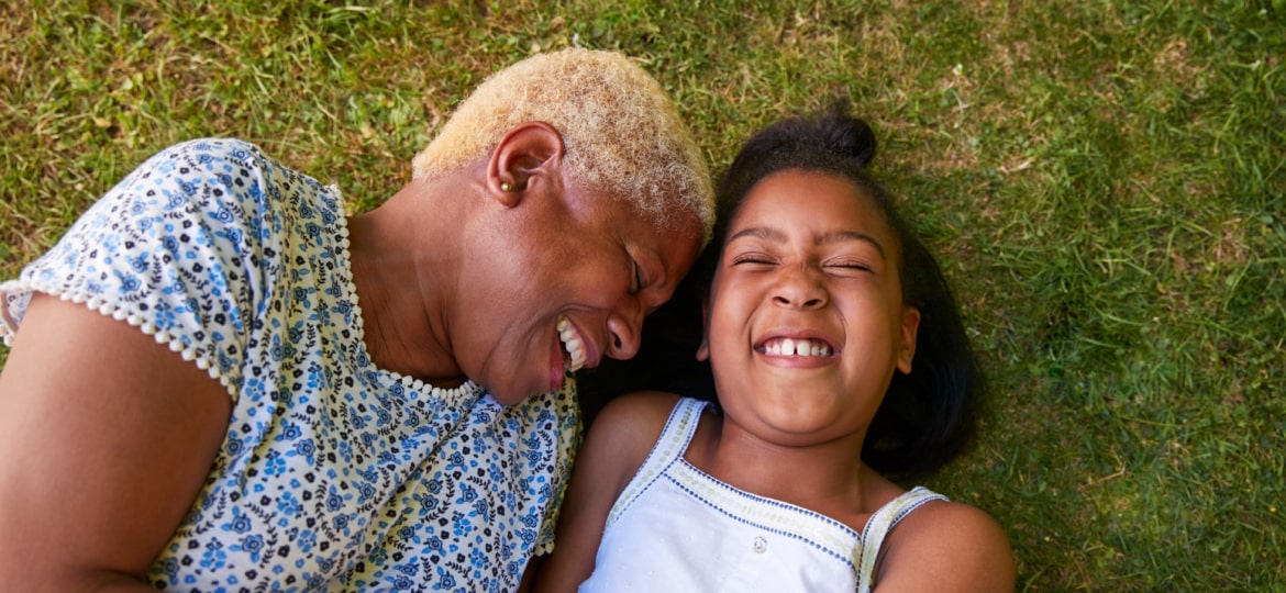 Grand-mother laughing with her grand-daughter on the grass