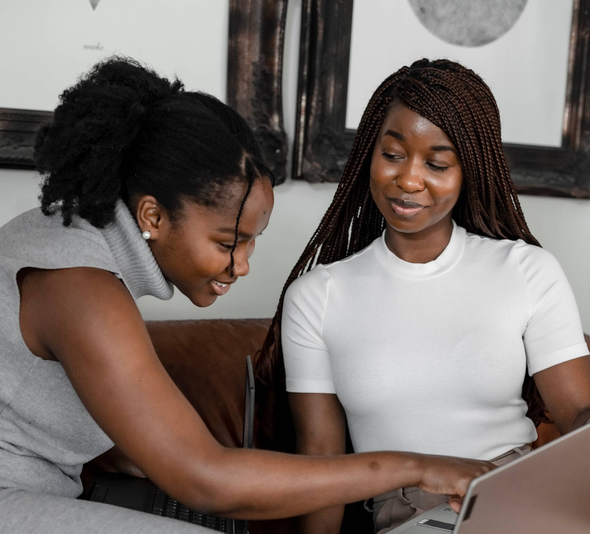 Two young black women looking intently at their laptop